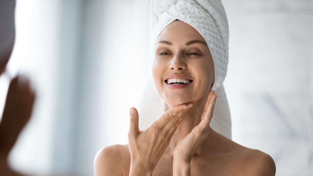 woman looking in mirror with towel on her head